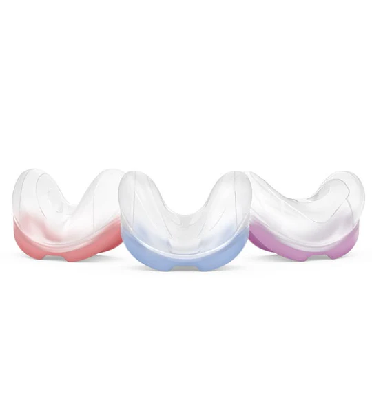 Trzy przezroczyste ochraniacze na zęby z kolorowymi podstawami: różową, niebieską i fioletową.