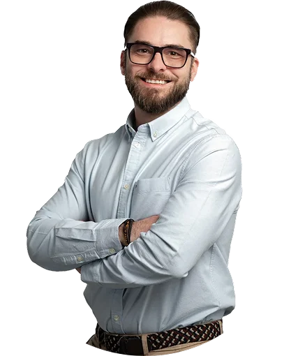 Mężczyzna w okularach stoi z założonymi rękami i uśmiecha się do kamery.